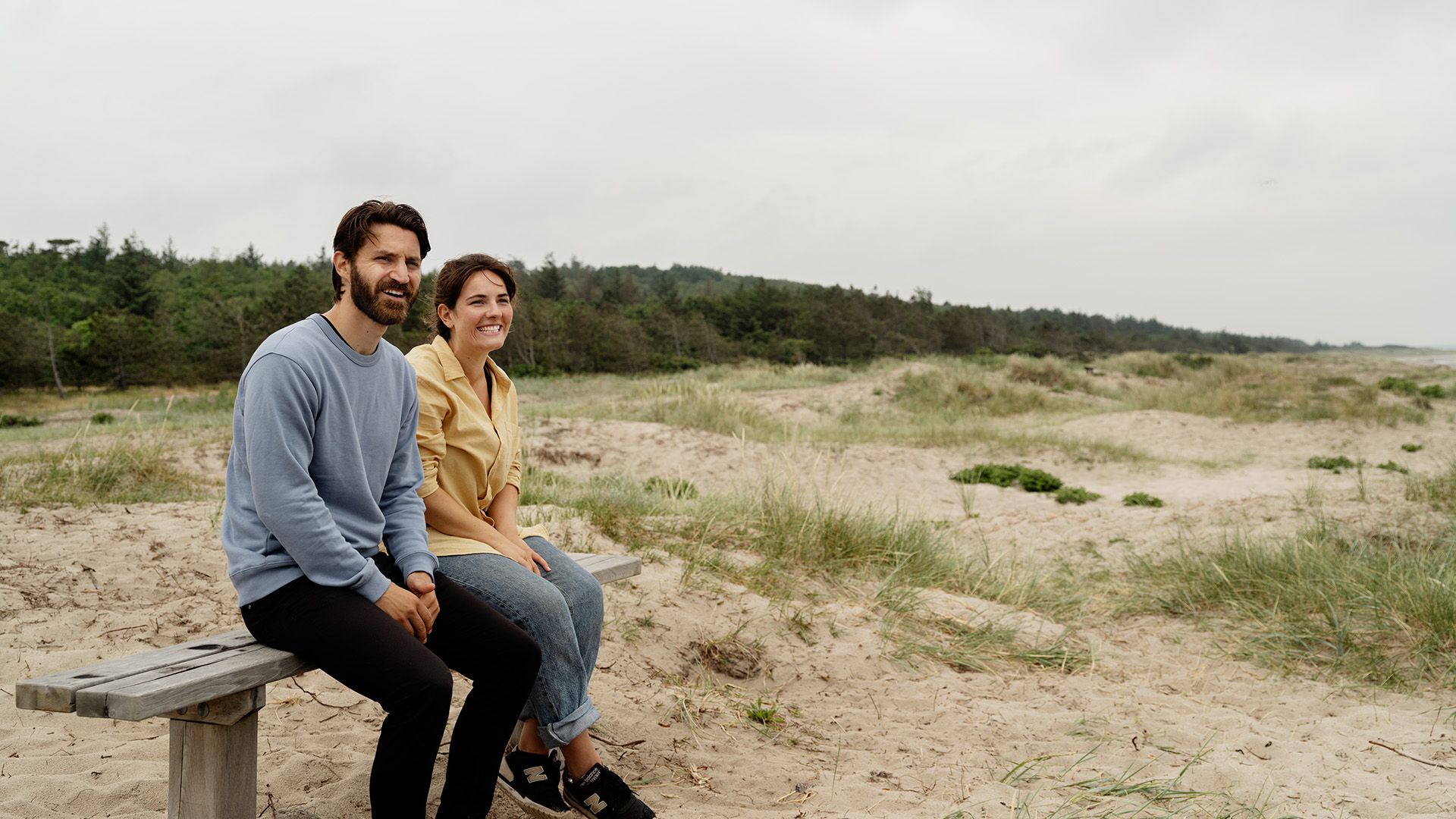 Mand og kvinde på dansk strand, hvor rejseforsikringen også dækker i tilfælde af ferie i Danmark.