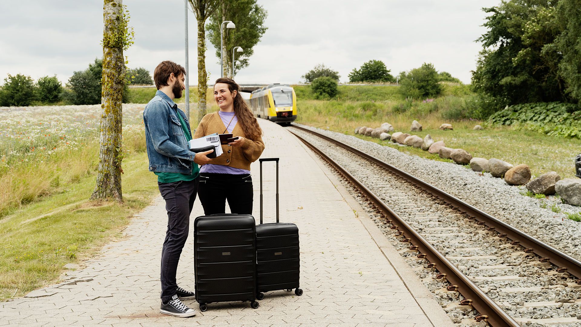 Par venter på toget på perronen, hvor rejseforsikringen og afbestillingsforsikringen også dækker i forbindelse i tilfælde af sygdom. 
